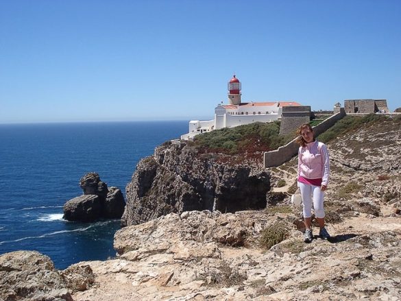 ženska stoji na pečini pred svetilnikom na rtu Cabo de São Vicente