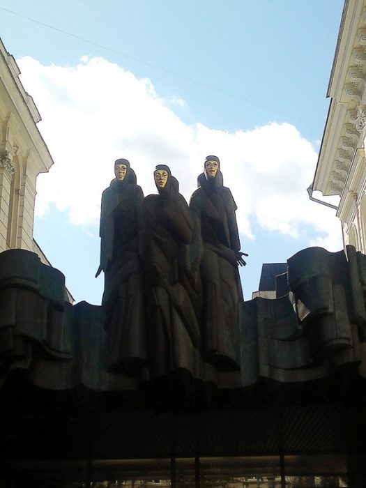 kip tri muze, tri ženske v črnih oblekah z zlatimi obrazi