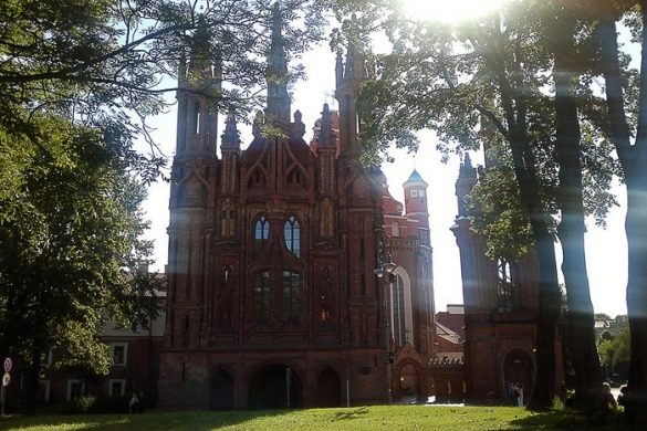 rdeča opečnata cerkev med drevesi, obsijana s soncem