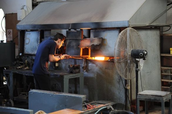 moški vzema žareče steklo iz peči