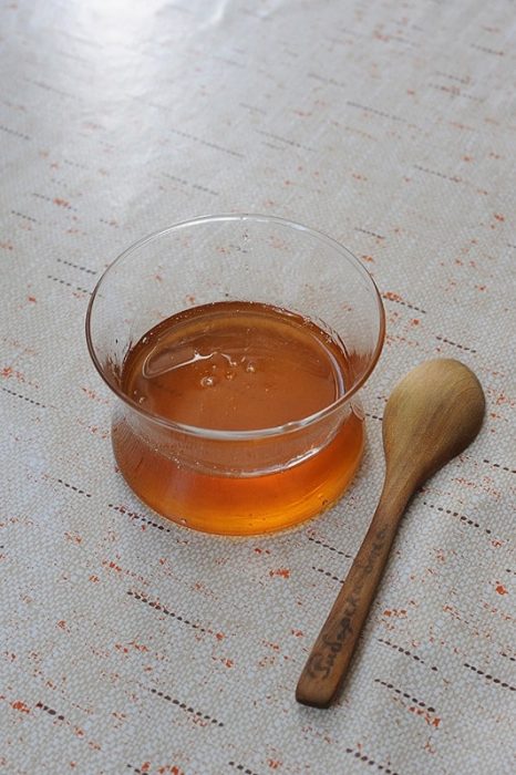 skodelica medu in lesena žlica poleg