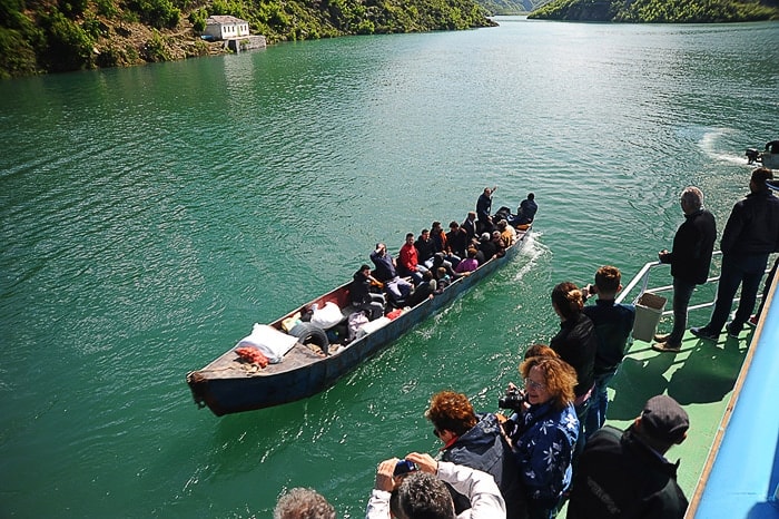 ozek čoln, poln ljudi na jezeru Komani