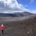 Ženska pohodnica v črni pokrajini pod vulkanom