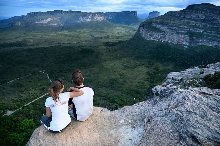 moški in ženska sedita na skali nad dolino. Chapada Diamantina, Brazilija