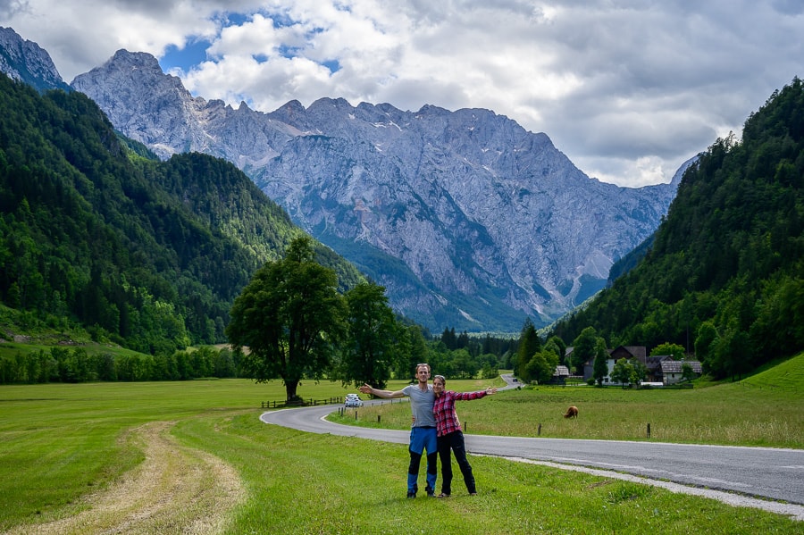moški in ženska na travniku pred logarsko dolino. v ozadju gore ter drevo lipa