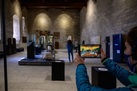 ženska drži v roki tablični računalnik s simulacijo nekdanje srednjeveške palače