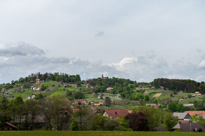 Dolenjska: pokrajina, griči, cerkev na vrhu hriba, zidanice in vinograd