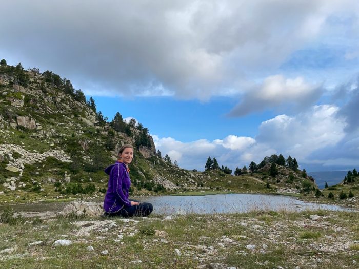 ženska sedi ob jezeru v Pirenejih. Andora. Žensko solo potovanje