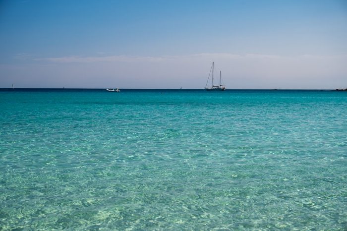 Top znamenitosti Sardinije: plaže! turkizno modro morje in jadrnica v daljavi