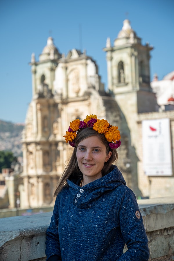 ženska z oranžnimi rožami v laseh pred cerkvijo v Oaxaca