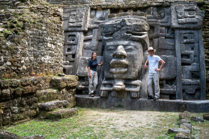 moški in ženska ob skulpturi obraza. Mask temple, Lamanai, Belize