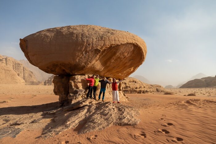 skupina mladih v Wadi Rum. Mushroom Rock skulptura v Wadi Rum