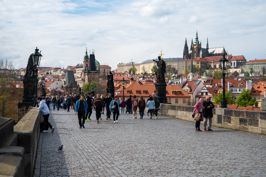 Ljudje se sprehajajo po eni izmed top znamenitosti Prage: Karlov most
