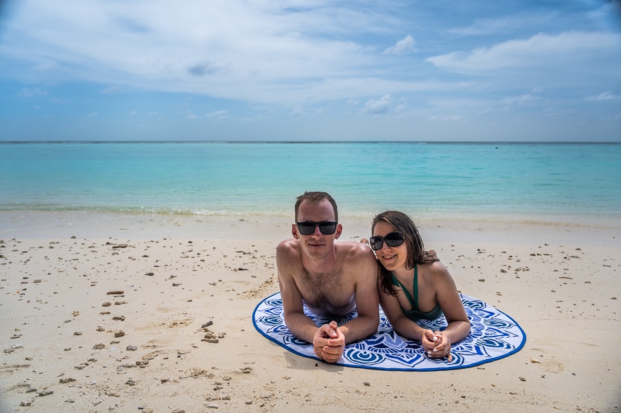 lokalni otok Thoddoo: moški in ženska ležita na brisači na vzhodni plači Thoddooja