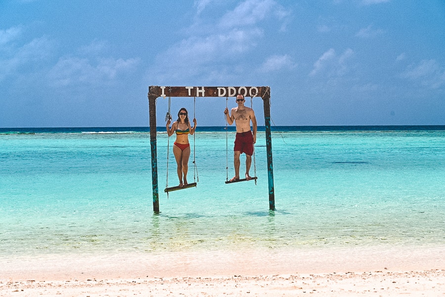 moški in ženska na gugalnici v morju, lokalni otok Thoddoo, Maldivi
