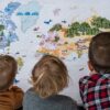 otroski zemljevid sveta - trije otroci gledajo zemljevid sveta
